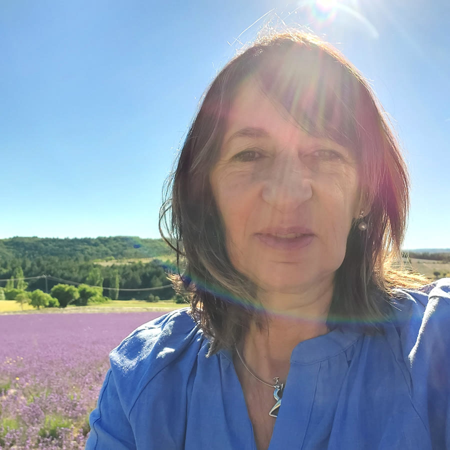 Marie, souriante, devant un champ de lavande en fleurs